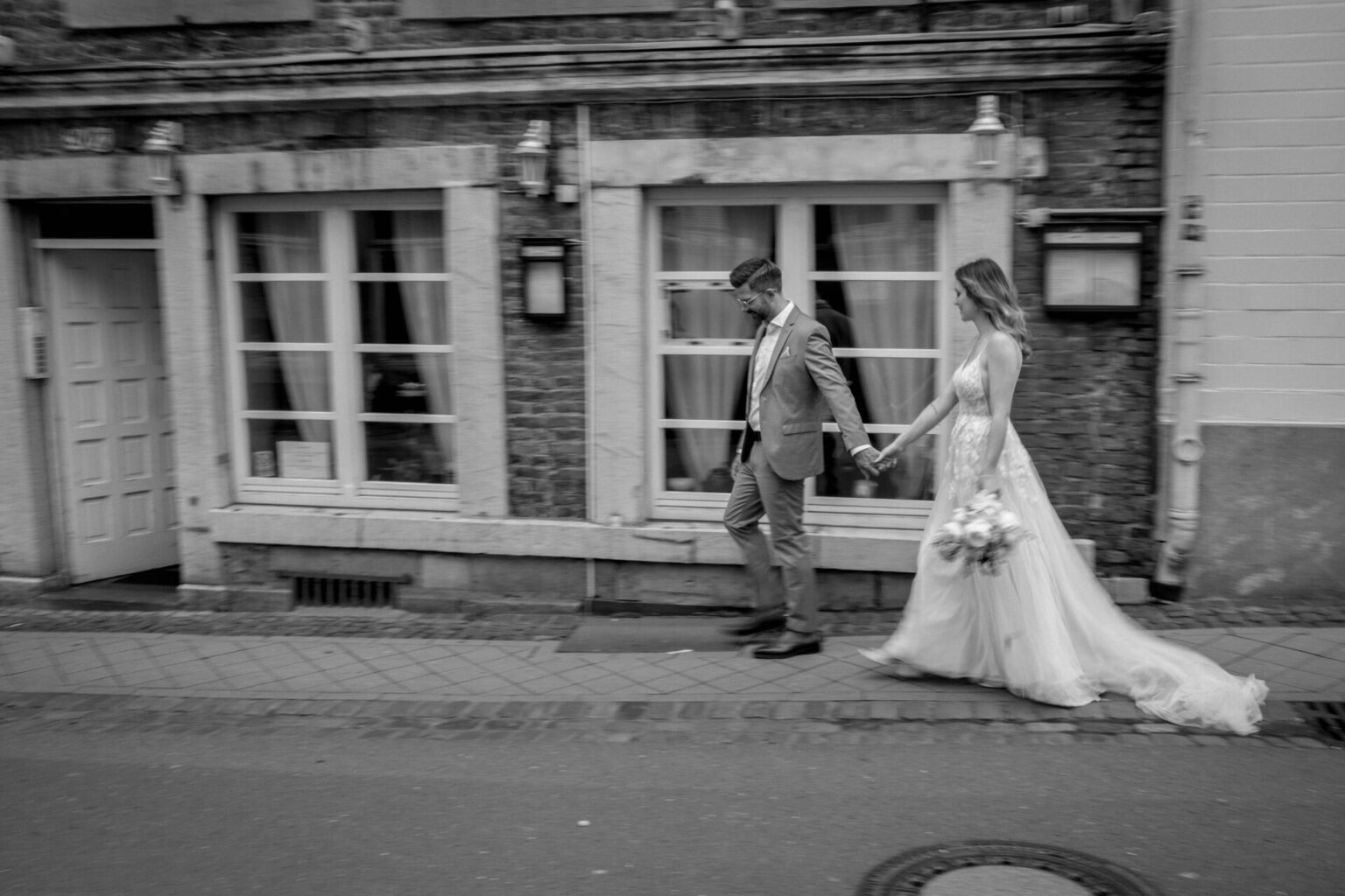 Hochzeitsfotograf aus Rosenheim fotografiert Brautpaar Hand in Hand durch die Stadt